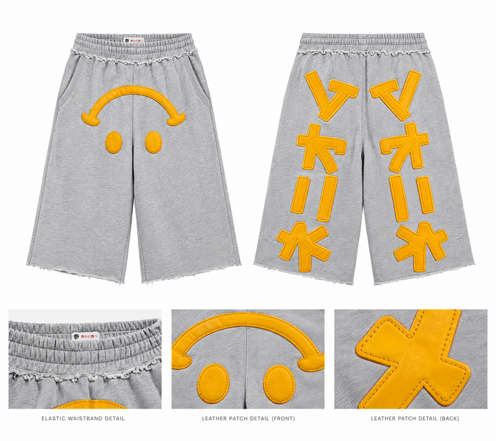 Light gray sweat shorts with yellow leather patch appliques on the front and back, shown on a white background with close-up detail insets of the waistband and leather patches.