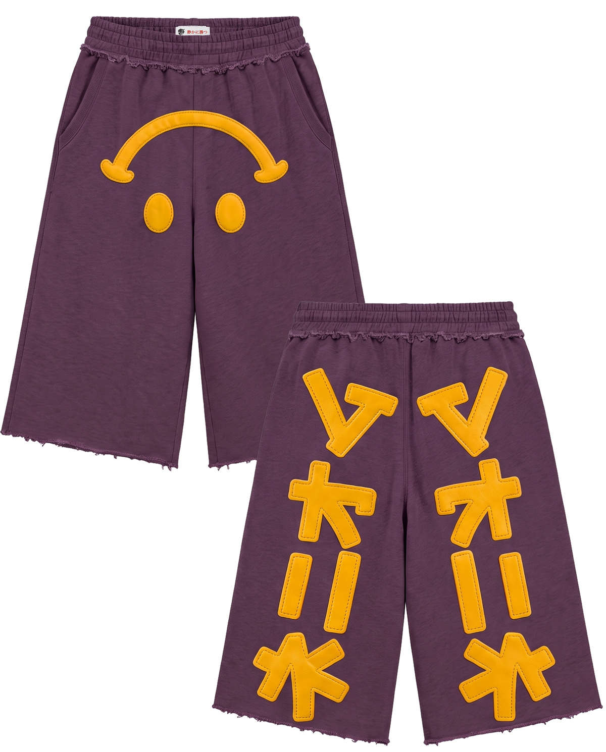 A pair of purple cropped sweat shorts with raw frayed hems, featuring a yellow smiley face patch on the left leg and yellow geometric patchwork designs on the right leg, shown against a plain white background.