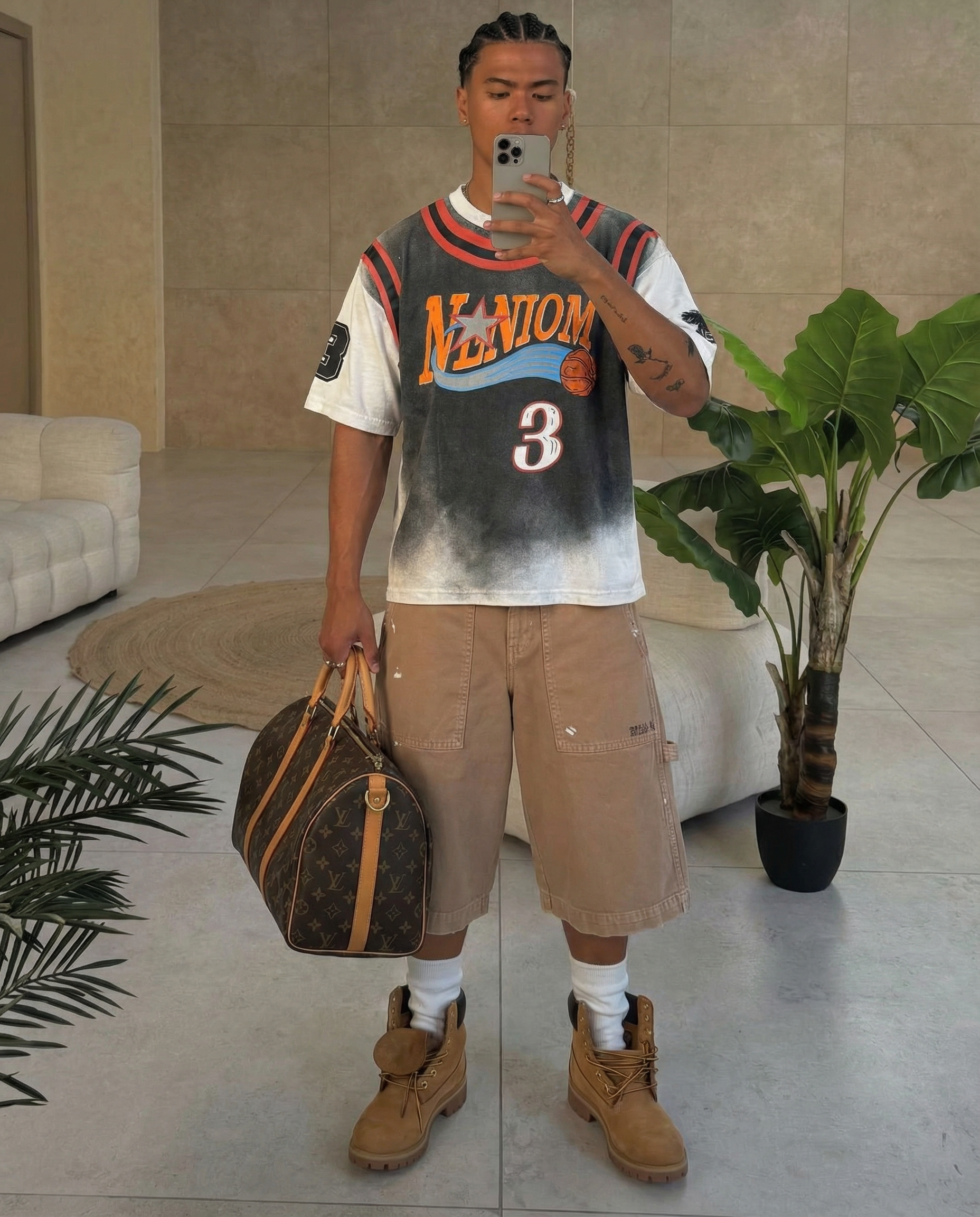 Man holding a Louis Vuitton bag indoors with plants and furniture in the background