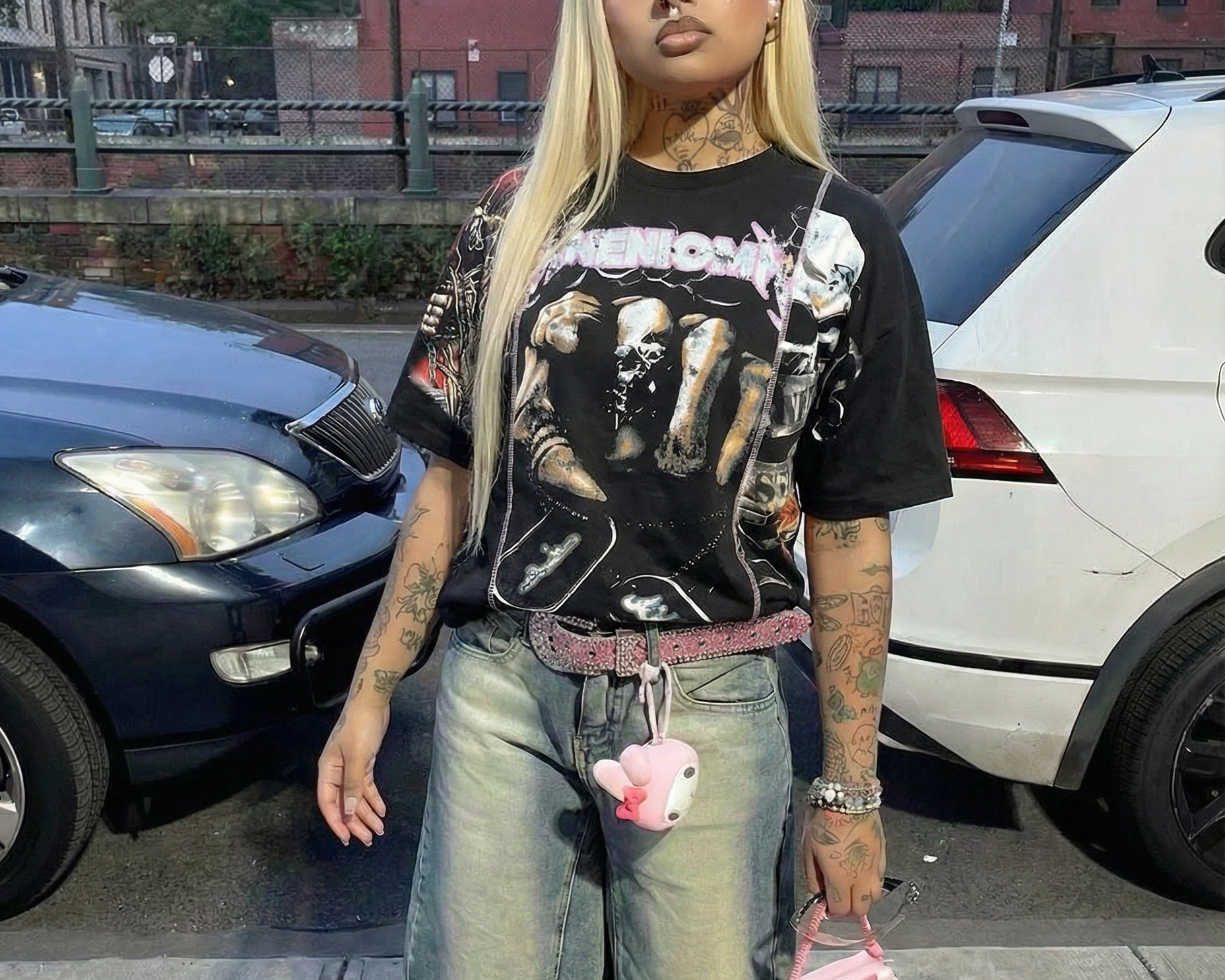 Person wearing a graphic t-shirt, denim shorts, and pink sneakers on a street.