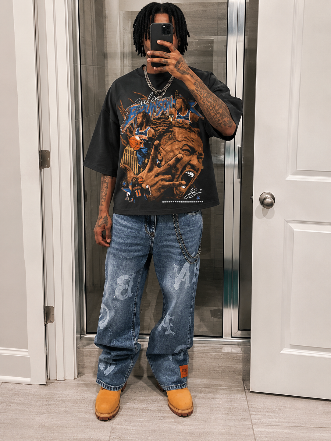 Person taking a mirror selfie wearing a graphic t-shirt, jeans, and yellow shoes. Jalen Brunson NYC Knicks Boxy Shirt Vintage Bootleg Streetwear Oversized Graphic Tee