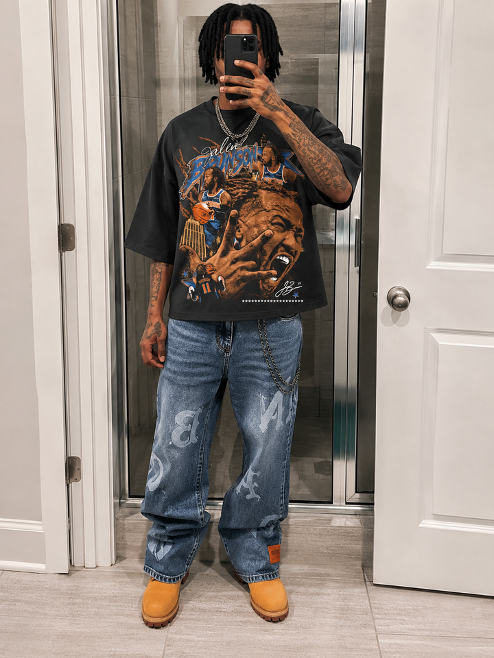 Person taking a mirror selfie wearing a graphic t-shirt, jeans, and yellow shoes. Jalen Brunson NYC Knicks Boxy Shirt Vintage Bootleg Streetwear Oversized Graphic Tee