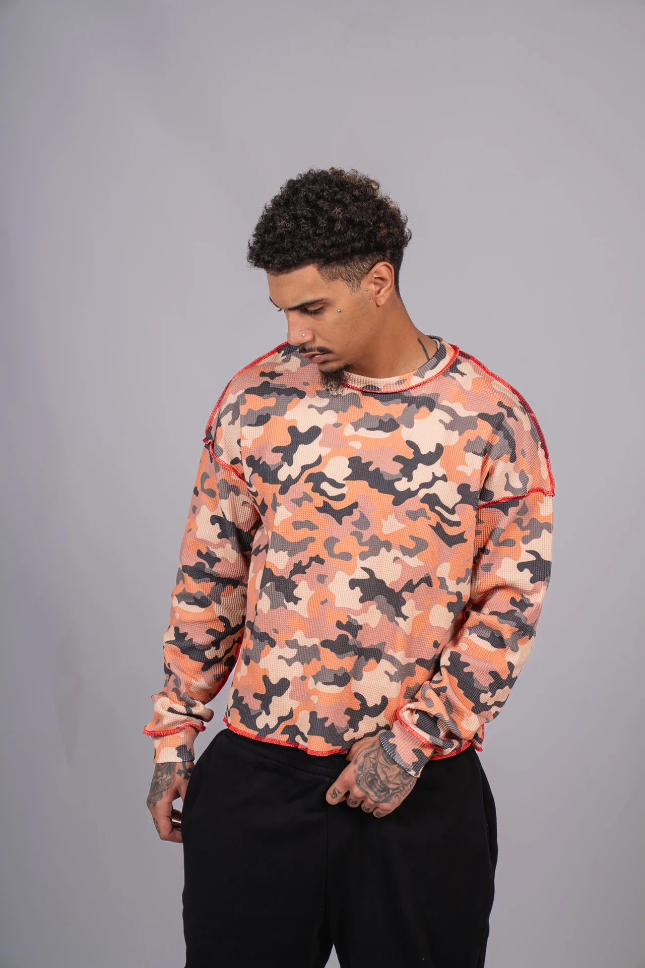 Man wearing a camouflage-patterned sweatshirt against a gray background
