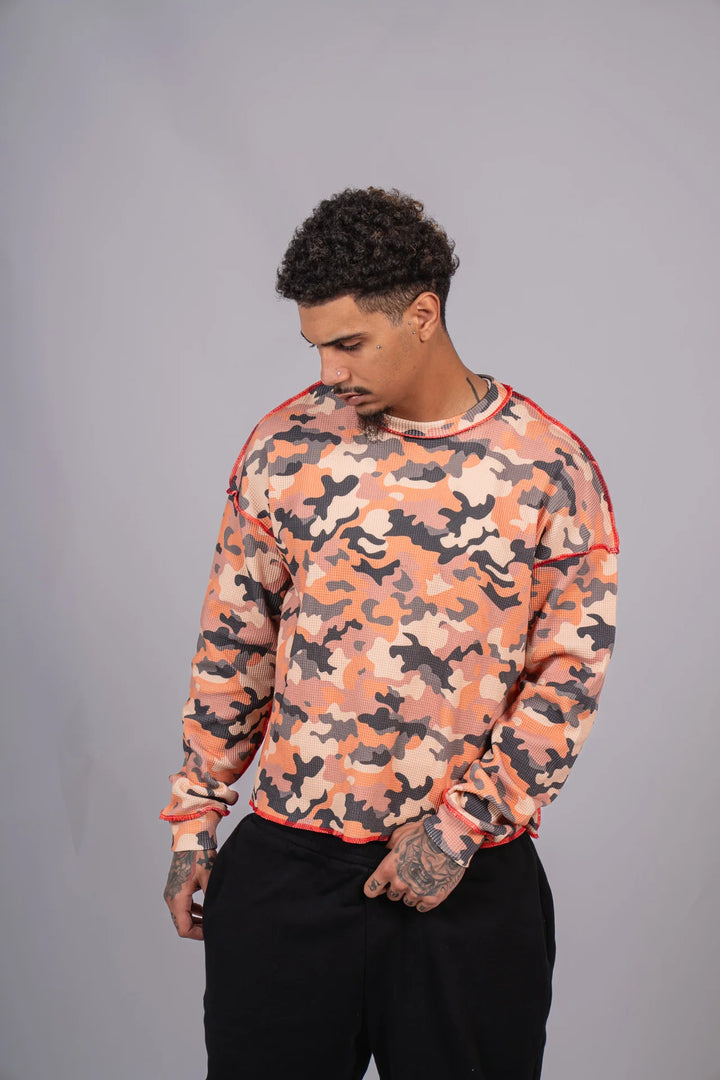 Man wearing a camouflage-patterned sweatshirt against a gray background