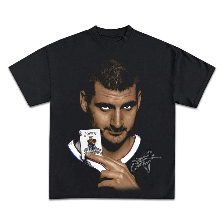 Black t-shirt with a graphic of a man holding a card with a joker design on a white background
