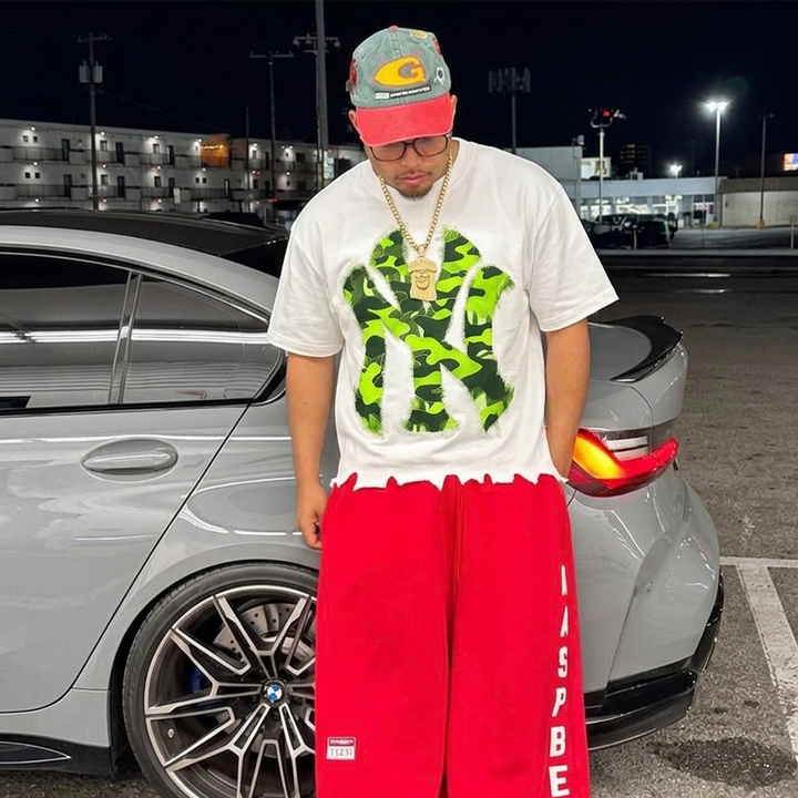 Neniom white oversized graphic tee with lime camouflage graphic; boxy fit, red shorts visible