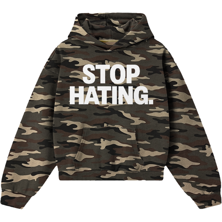 A camouflage hoodie with the words 'STOP HATING.' printed in bold white capital letters across the chest, shown on a plain white background.