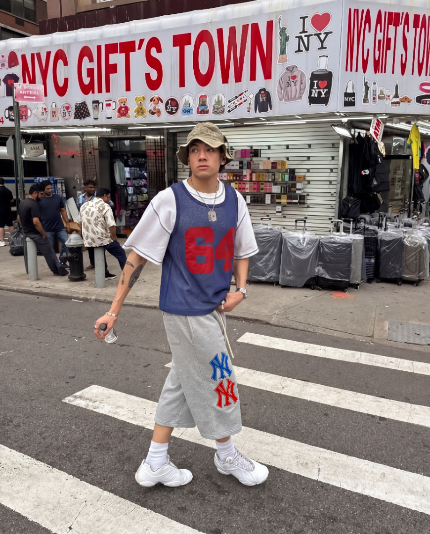 Person standing on a street corner in front of 'NYC Gifts Town' store. y2k streetwear fashion outfit