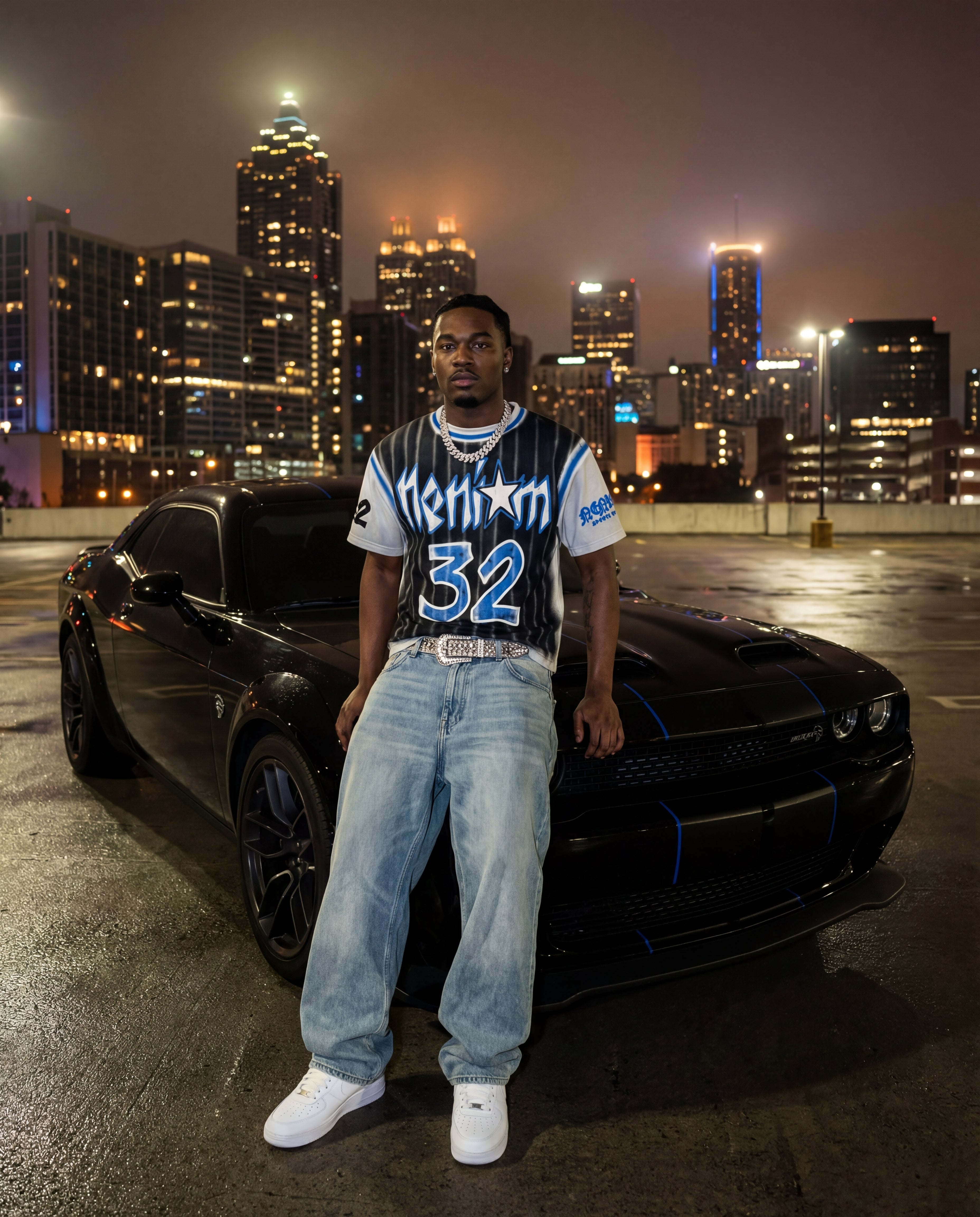 Man standing next to a black car with a city skyline in the background at night.