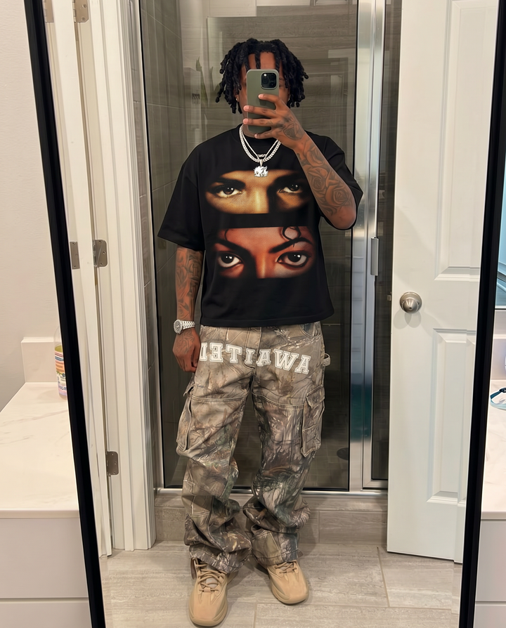 Person wearing a black t-shirt with a graphic design and camouflage pants in a bathroom. Drake & Michael Jackson Vision Boxy Shirt Vintage Bootleg Streetwear Oversized Graphic Tee
