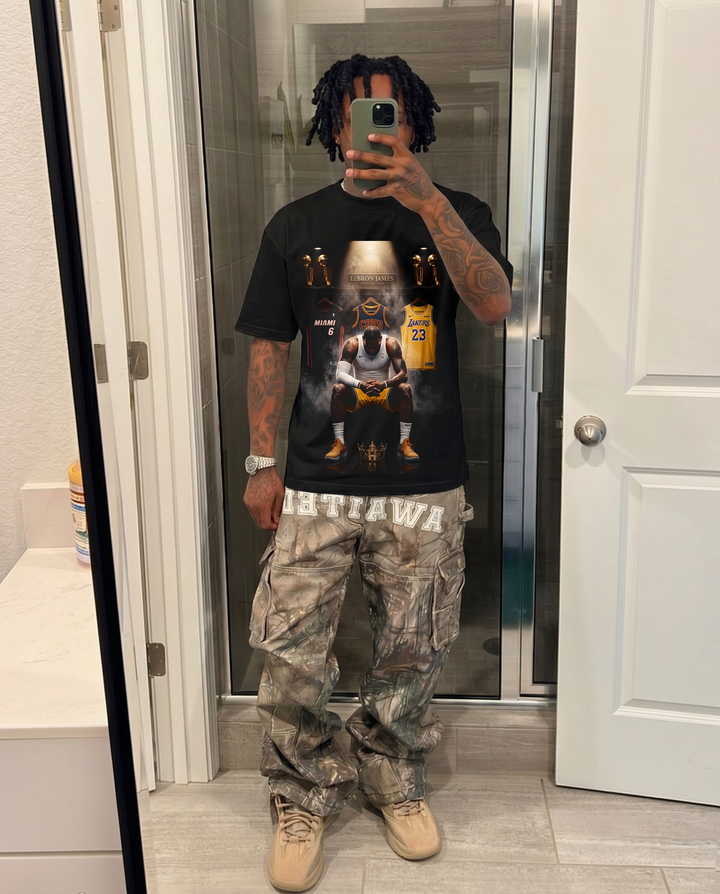 Person wearing a black graphic t-shirt and camouflage pants in a bathroom. Lebron James Showcase Shirt Vintage Streetwear Oversized Artist Graphic Tee
