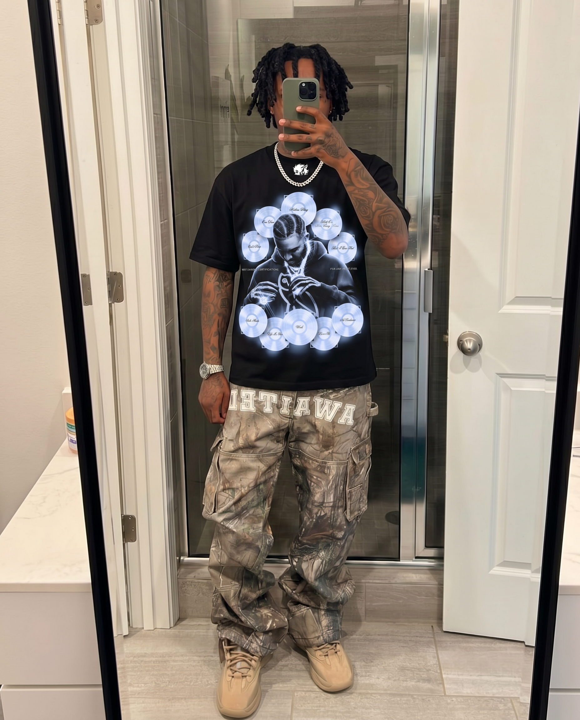 Person wearing a black t-shirt with a graphic design and camouflage pants in a bathroom. Drake Carrer Icon Boxy Shirt Vintage Bootleg Streetwear Oversized Graphic Tee