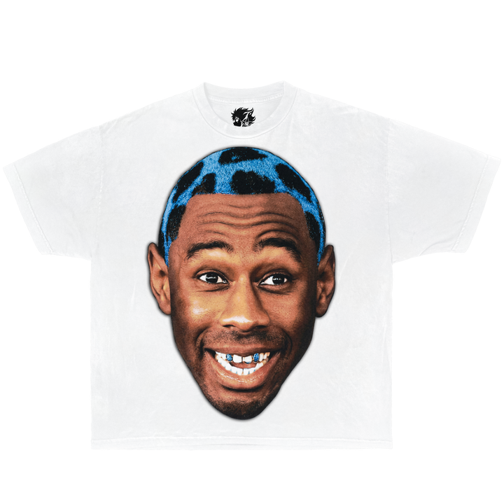 White graphic t-shirt featuring Tyler The Creator face portrait design with blue hair and retro hip hop streetwear aesthetic.